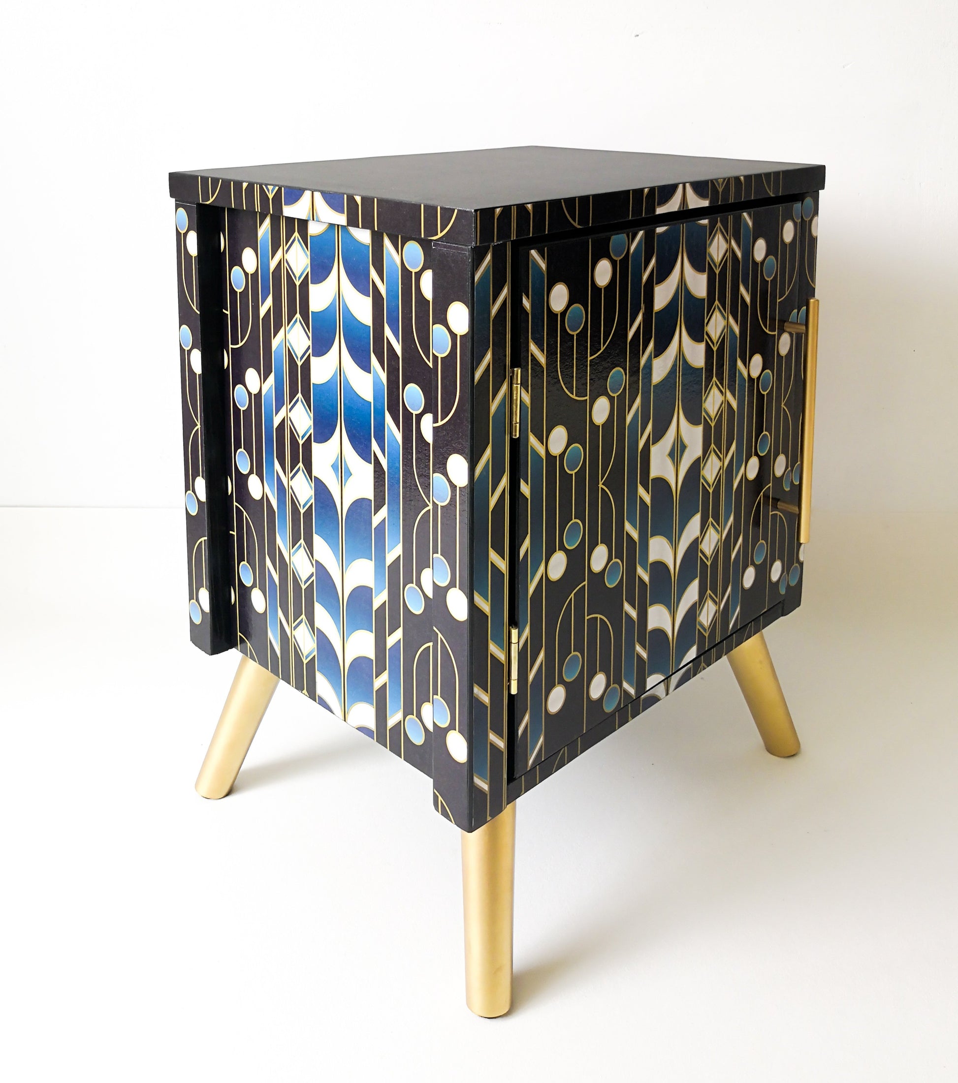 Upcycled modern bedside table decorated with Oriental geometrical pattern. Has gold legs and T-bar gold handles. 